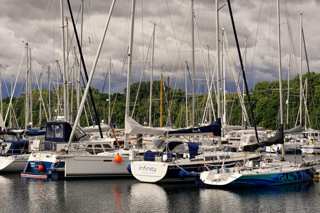 A picturesque scene of sailboats docked at a serene marina under a cloudy sky in Germany.